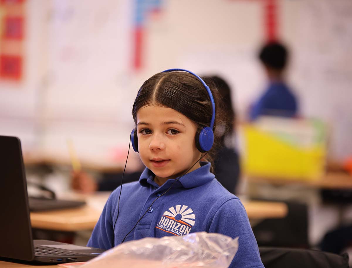 Elementary student smiling and posing together in a classroom.